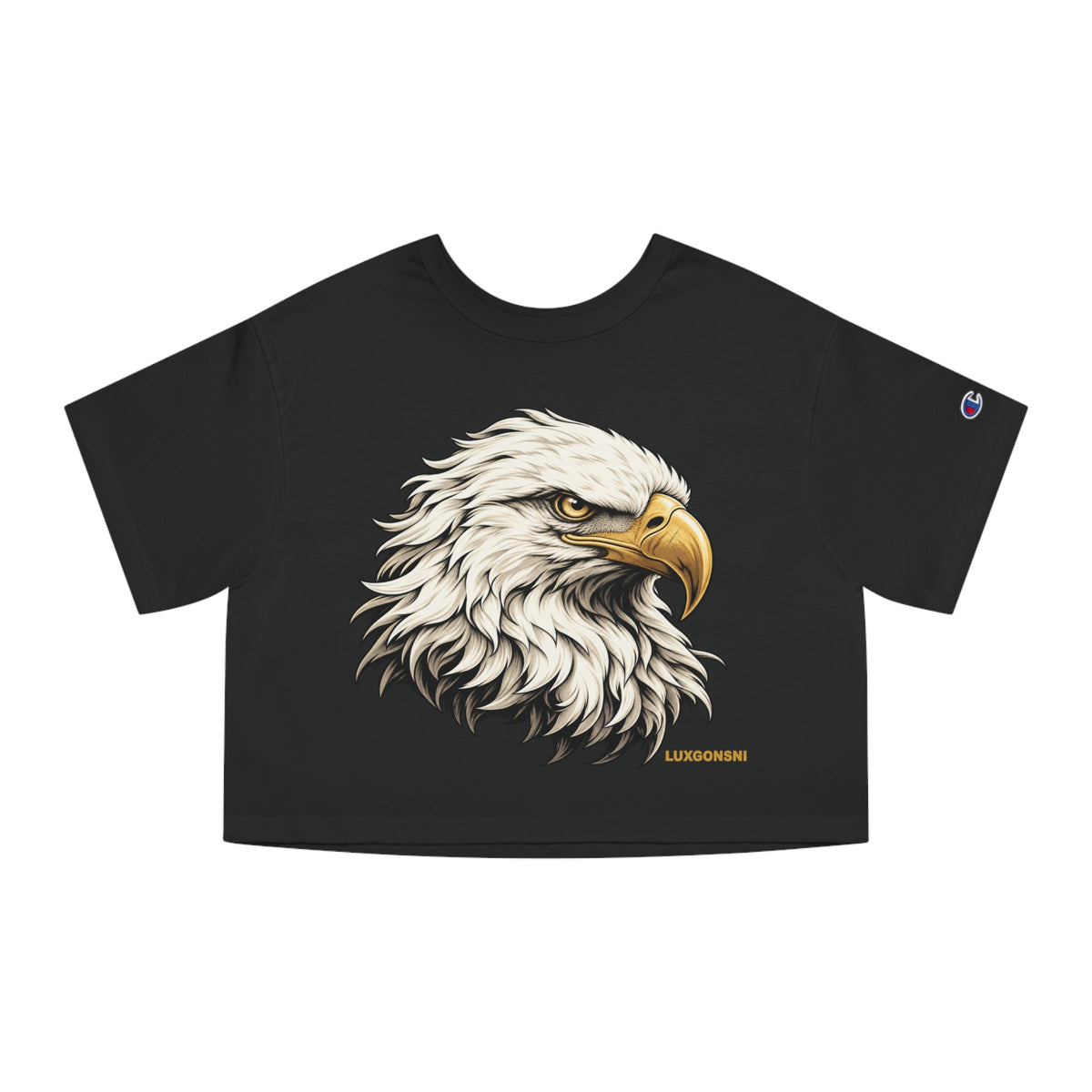 A black short-sleeve crop top t-shirt featuring a detailed graphic of a bald eagle's head on the front, with a small Champion logo on the left sleeve and 'LUXGONSNI' printed in gold near the bottom hem.